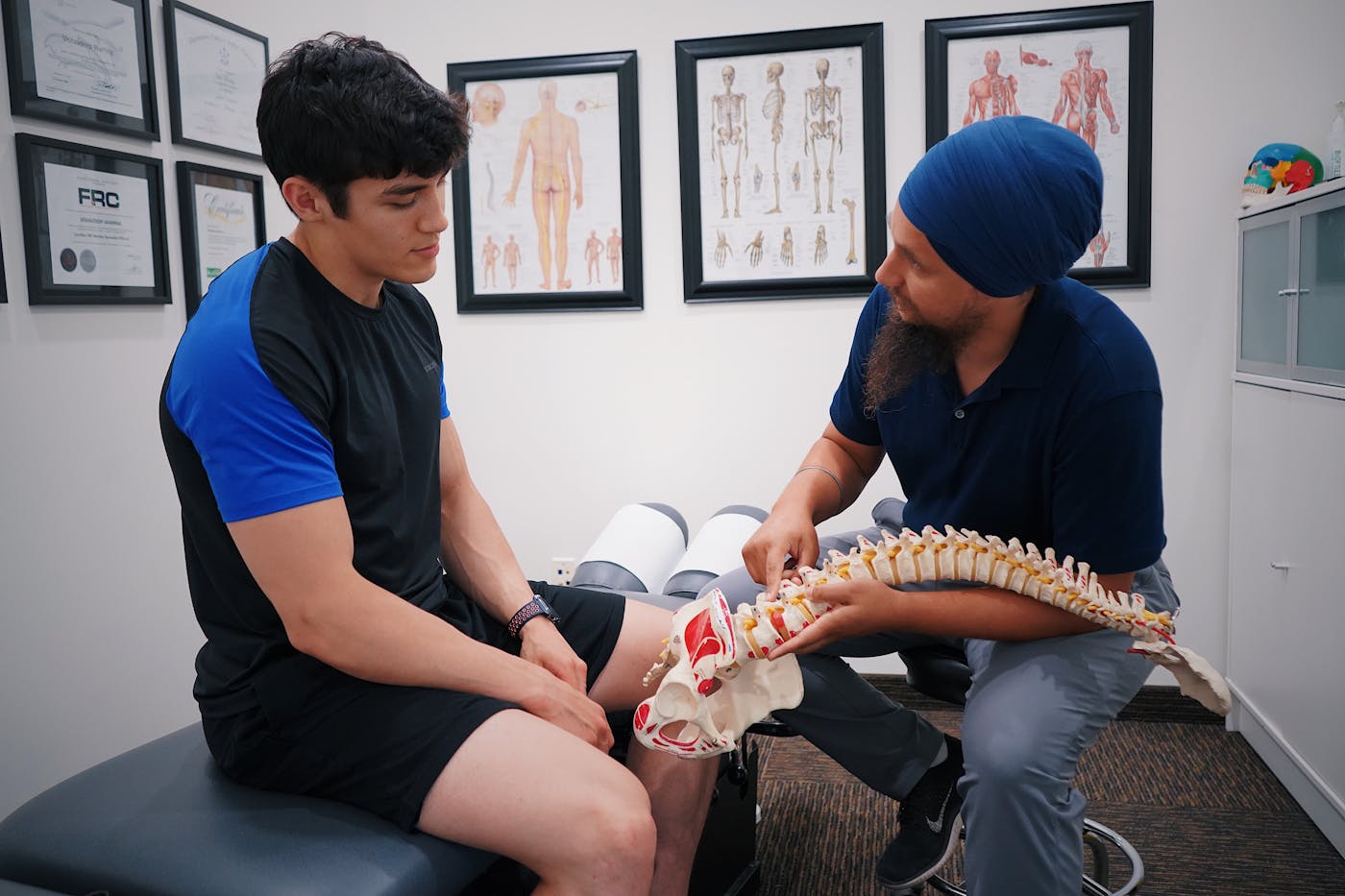 Chiropractor explaining spinal anatomy to a patient using a spine model